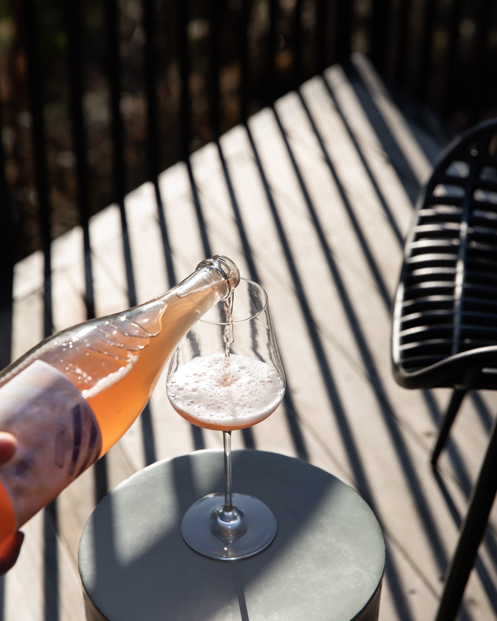 A glass of sparkling Tasmanian rose being poured on the sunlit deck of a Hunter cabin