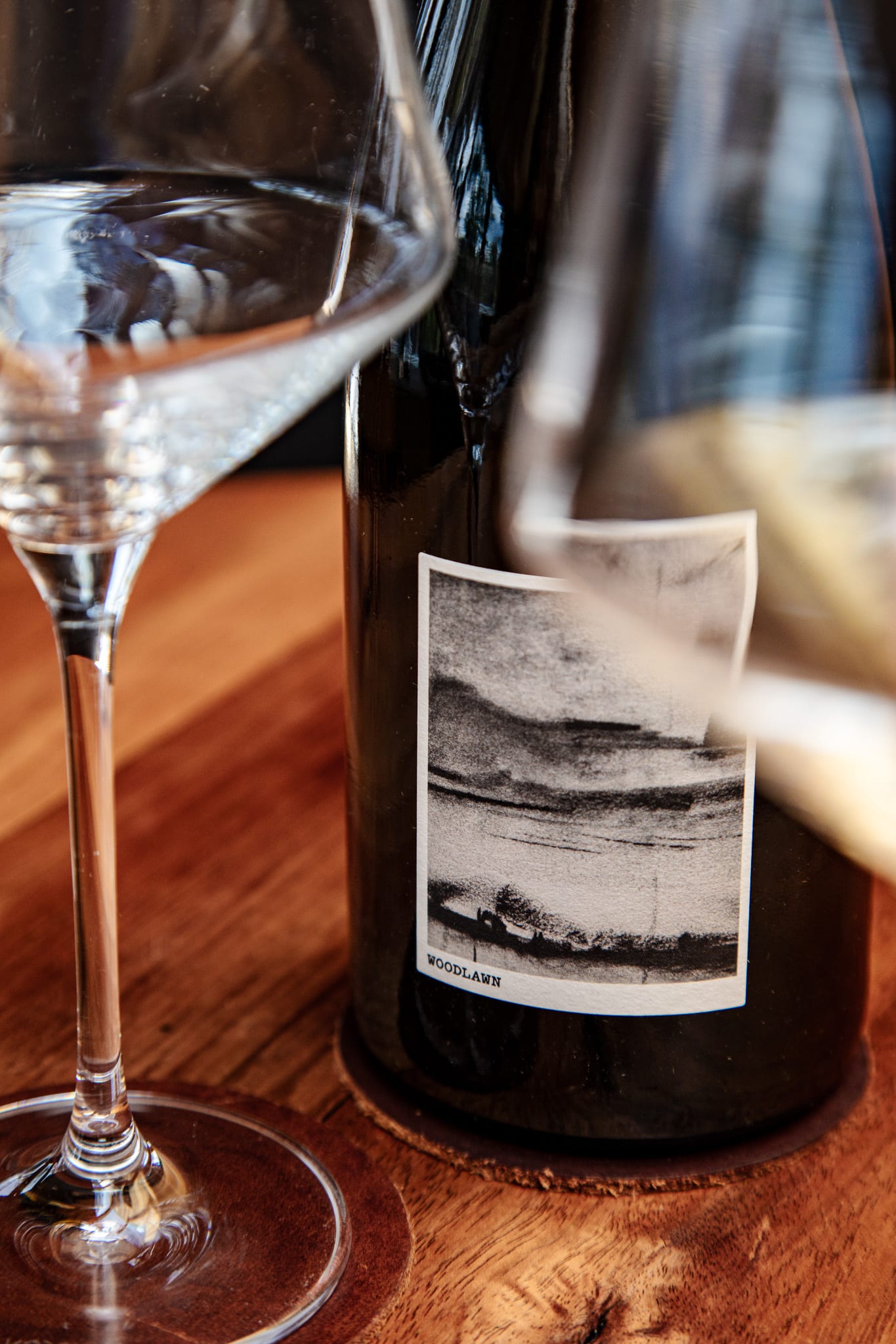 An open bottle of cool-climate Tasmanian white wine beside a poured glass on a timber table
